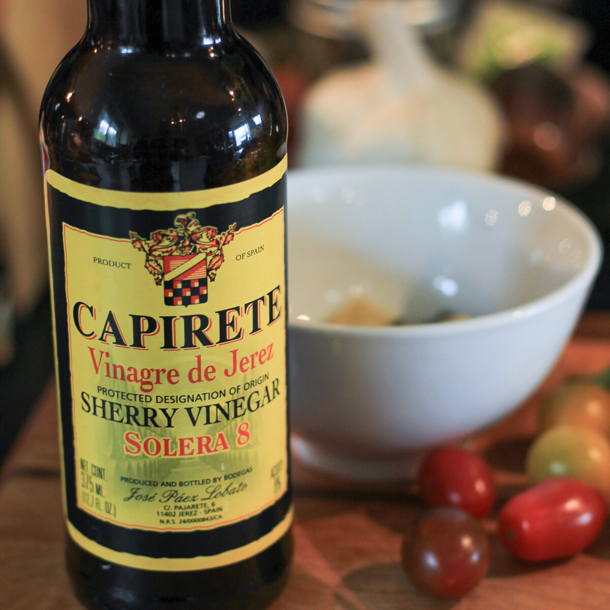 Sherry vinegar beside a small white bowl to make the Nicoise salad dressing