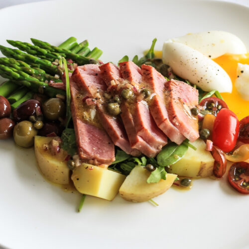 Rare sliced tuna with potatoes, soft boiled egg and asparagus presented as salad nicoise