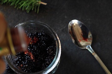 Blackberries in a mason jar with a spoon beside.