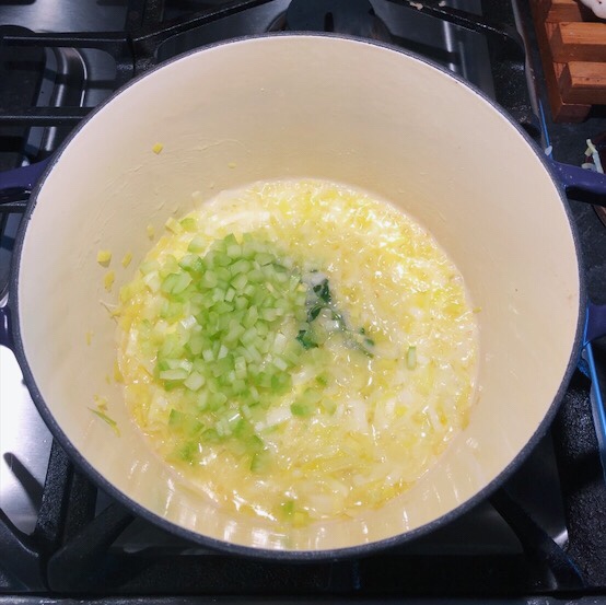 Chopped celery and thyme have been added to the sautéed onion in the pot.
