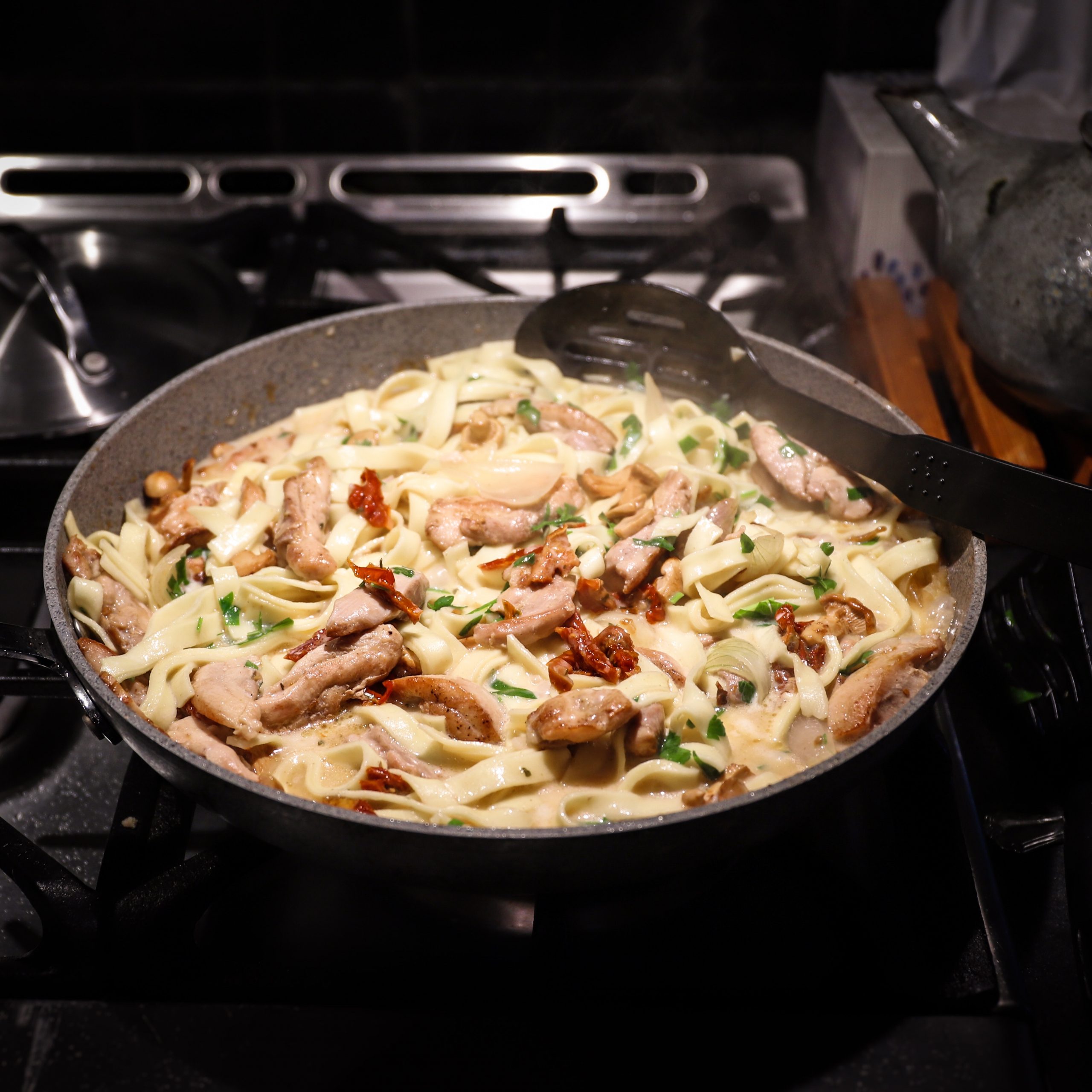 Chicken and and mushroom pasta in its cooking pan. It looks creamy and is ready to serve. 