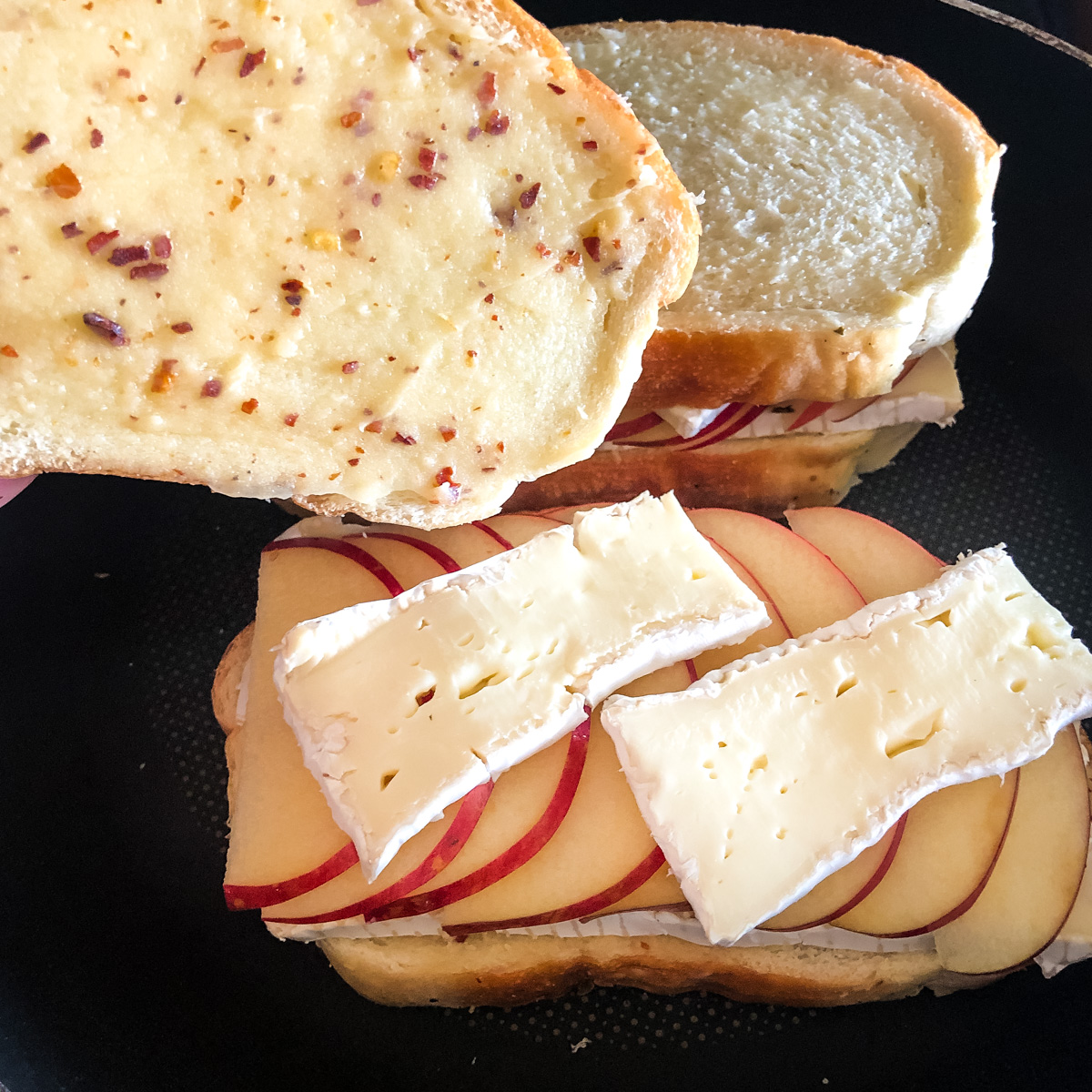 Layering thinly sliced brie and apples before grilling sandwich