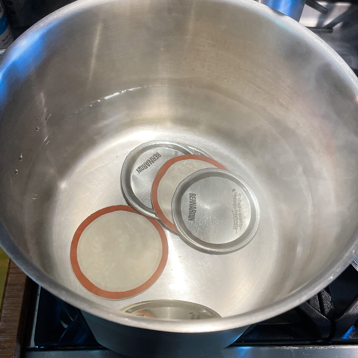 Canning jar lids in hot water bath being sterilized