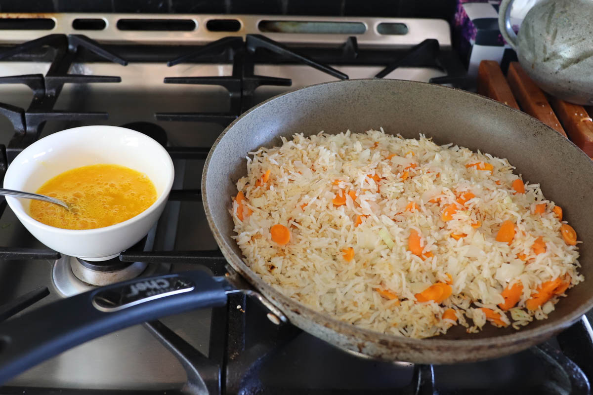 Rice in frying pan now has carrots and onions added. The beaten eggs are in a bowl beside, ready to be added.