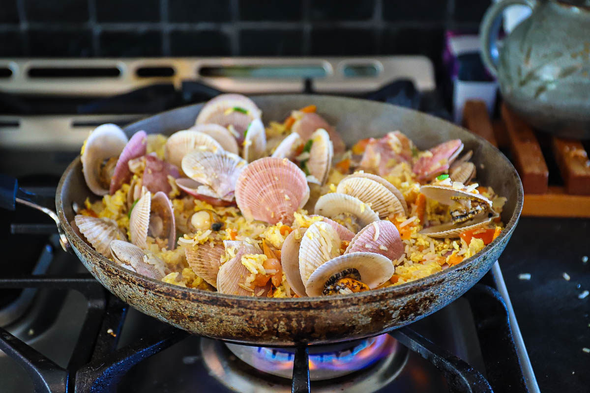 Scallops have cooked quickly and the shells are open and peeking out of the fried rice in the pan