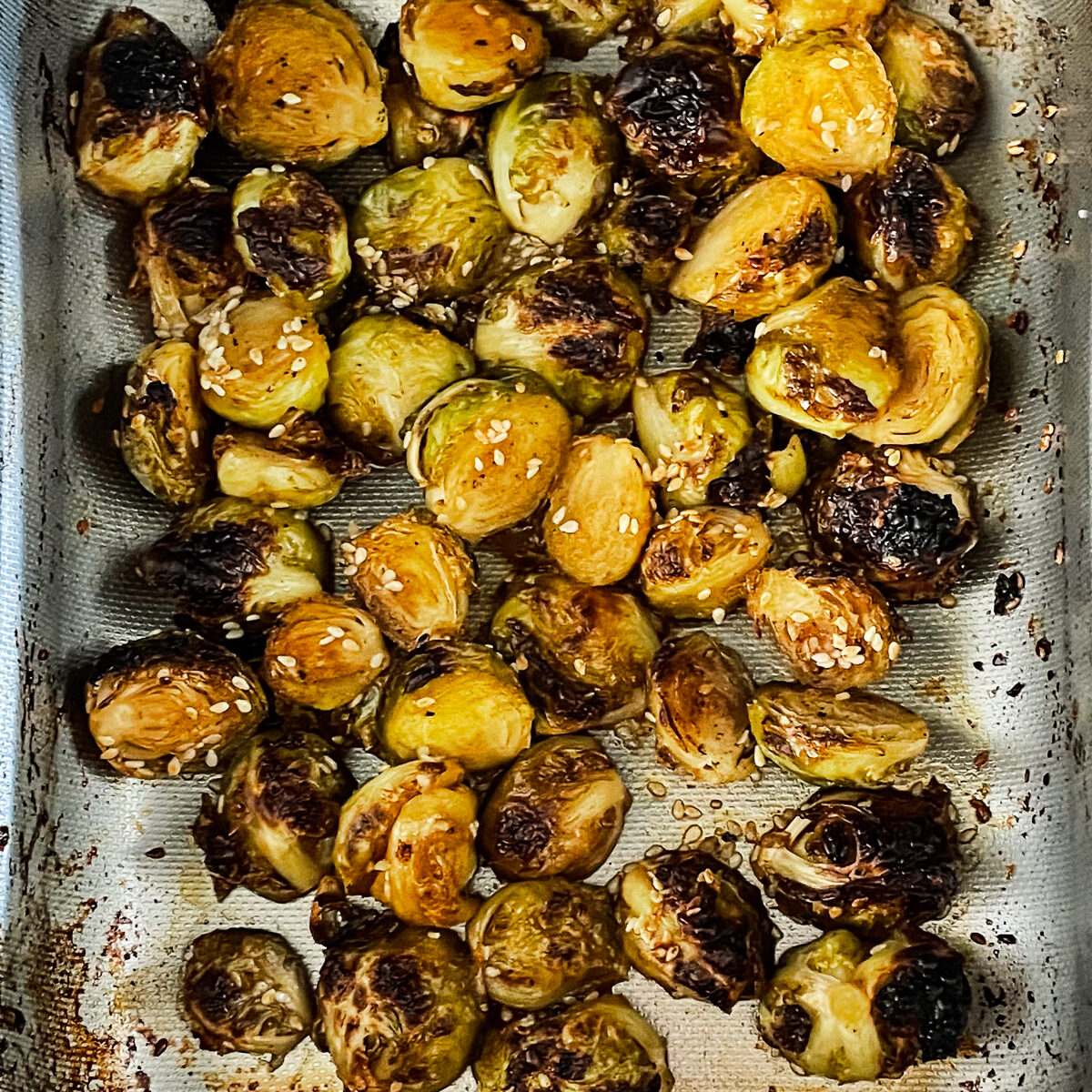 The halved brussel sprouts are roasted and crispy with dark brown spots and sesame seeds throughout.