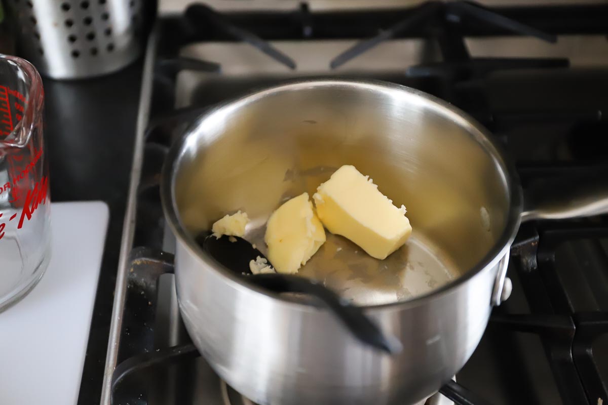 Two chunks of butter (¼ cup) in a saucepan ready to melt.