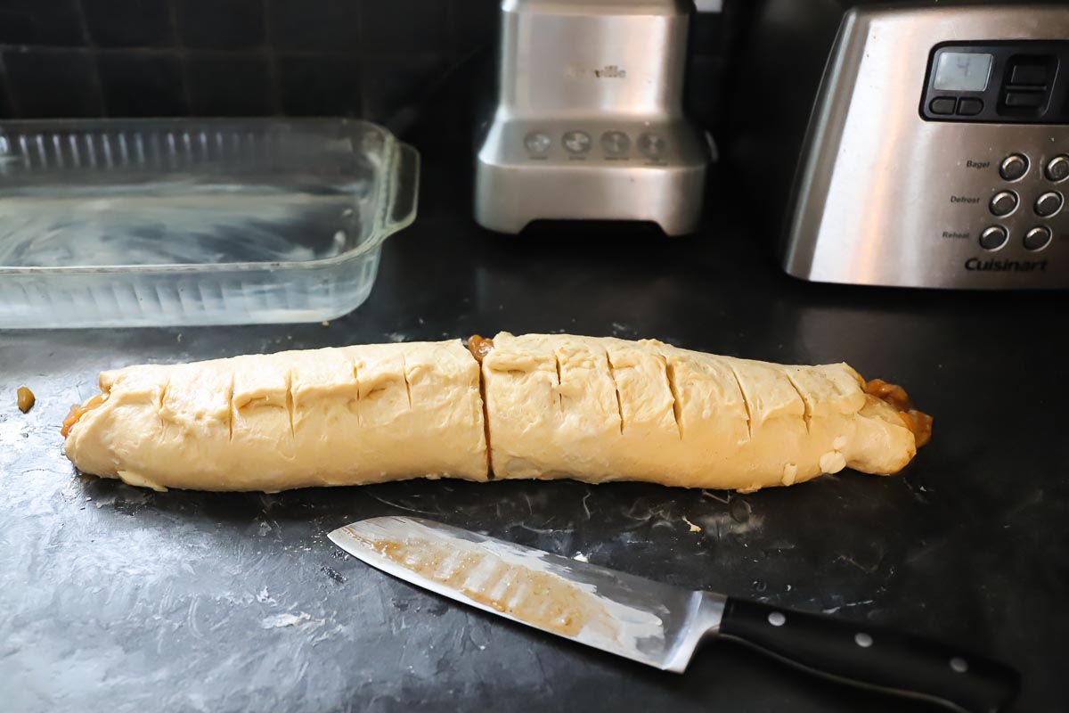 A sharp buttered knife has scored the dough into 12 equal sections.