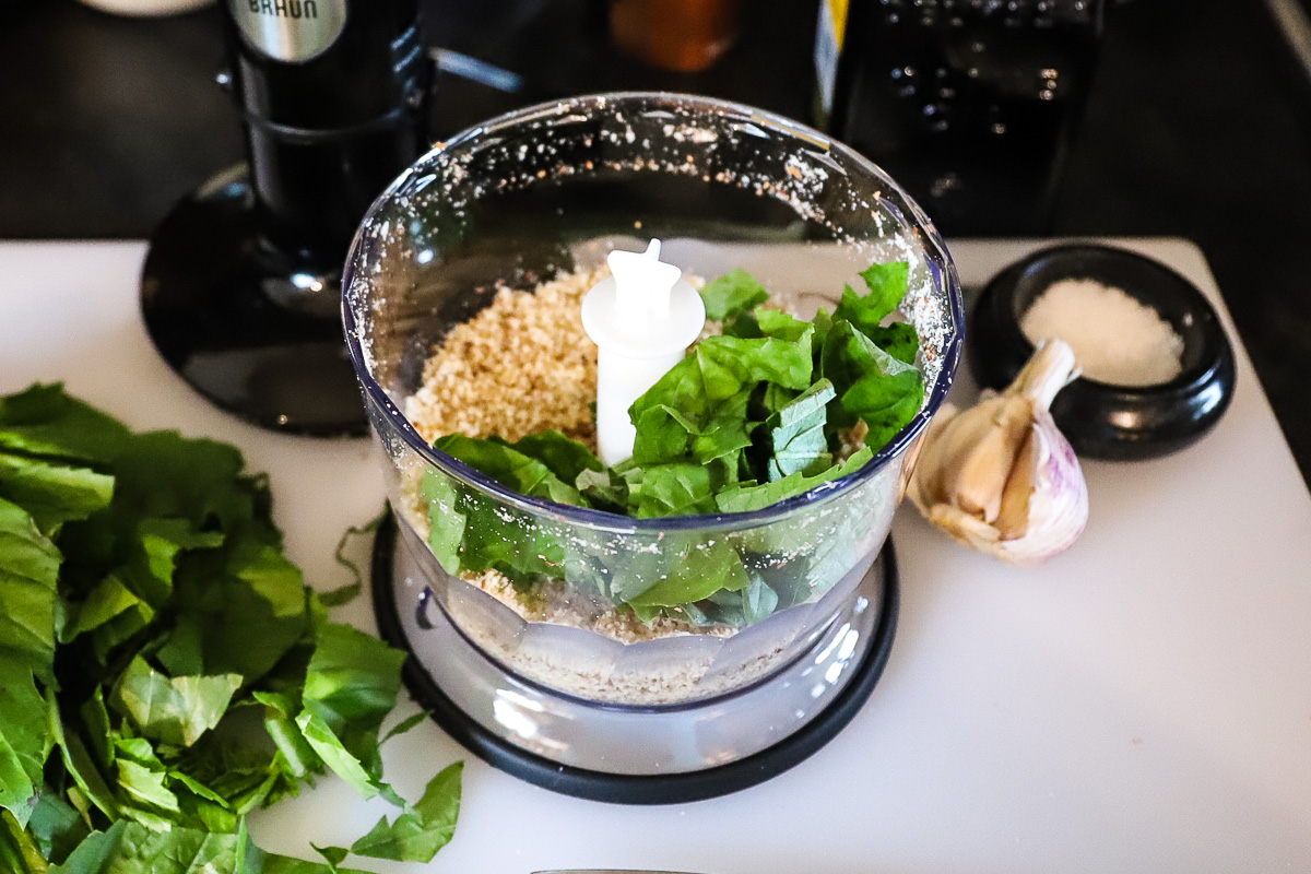 The first half of the basil has been added to the food processor with the chopped almonds and garlic.