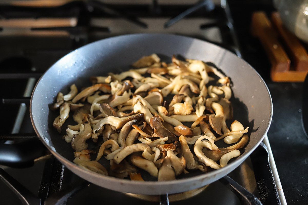 Gently sauteed mushrooms in frying pan are starting to turn gold brown in places.