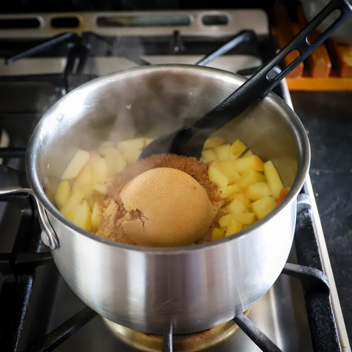 The cooking apples in the pot have the brown sugar added in a lump on top.