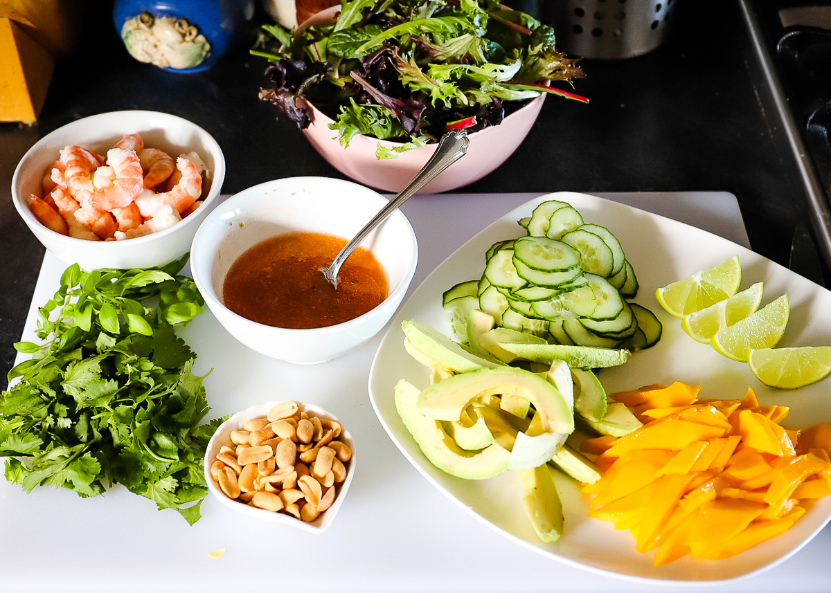 All the ingredients for the Thai shrimp salad are cut and ready on a plate and cutting board.