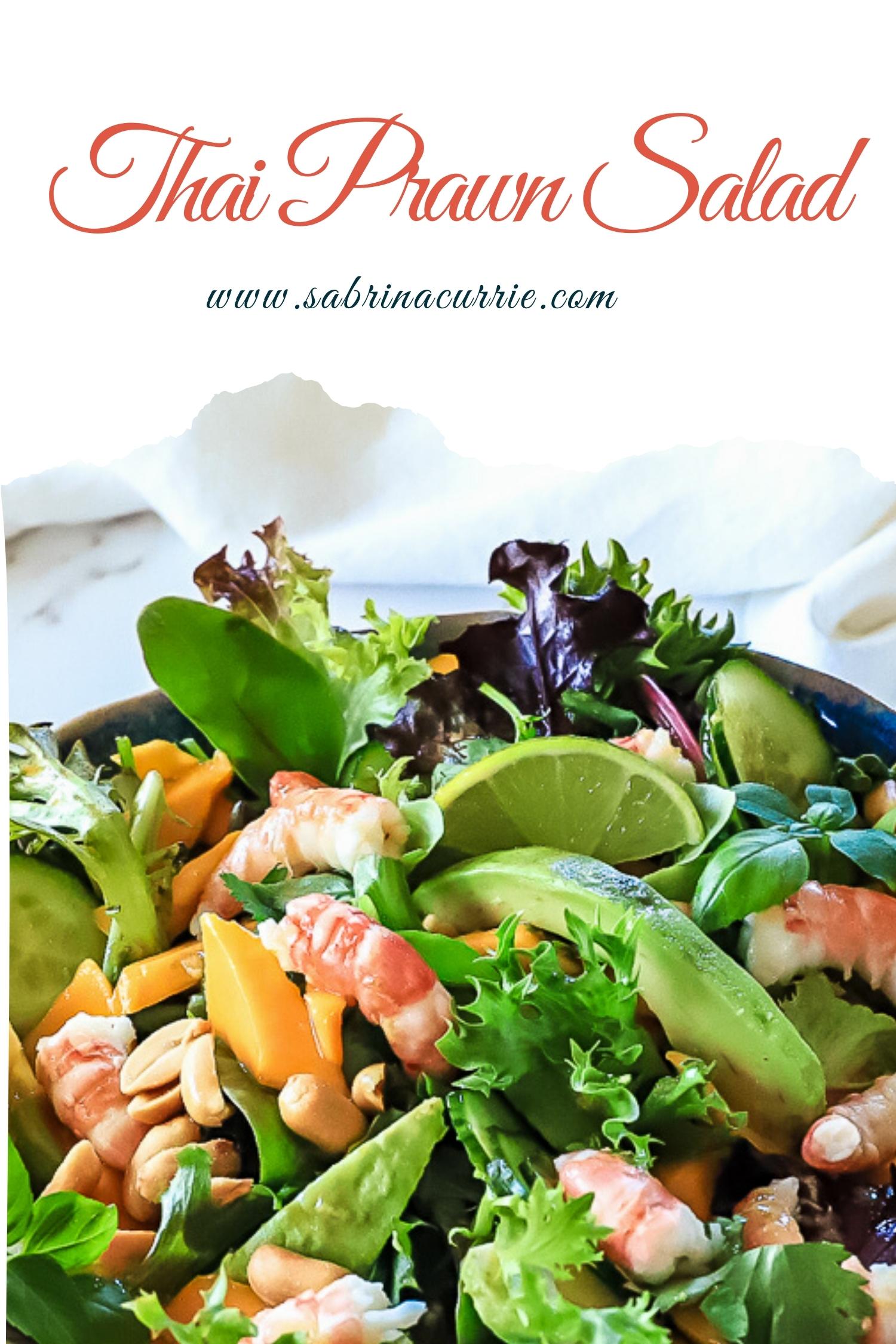 A closeup of the salad showing peeled pink prawns, bright green leaves and orange mango below text showing recipe name and blog site sabrinacurrie.com.