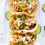 Three soft shell tacos filled with fish, coleslaw and jalapenos and drizzled with mayonnaise sauce.