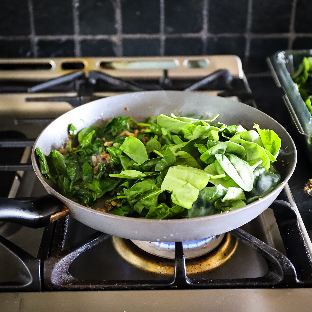 Second addition of spinach (aka palak) added to pan of cooked spinach.