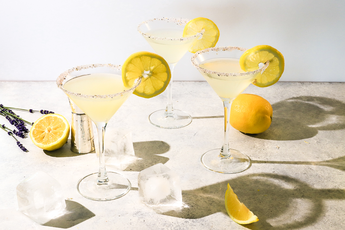 Three pale yellow colored lavender lemon drop martini's garnished with a wheel of lemon each. 