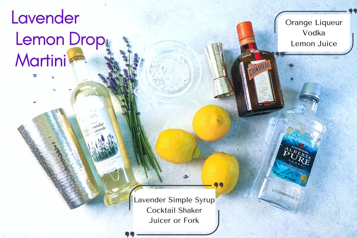 Overhead picture of ingredients and equipment for the lavender lemon cocktail, including a silver cocktail shaker, bottle of lavender syrup, bundle of fresh lavender flowers, 3 lemons, a shot measure, cointreau bottle and bottle of vodka with text overlay labelling it all.