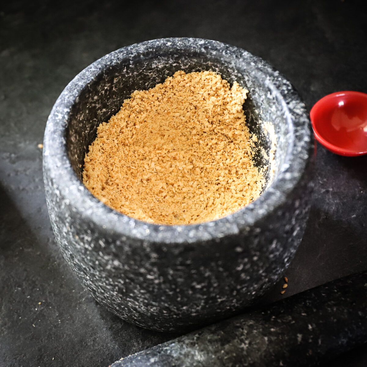 The roasted sesame seeds have been ground to a mealy paste texture with the mortar and pestle.