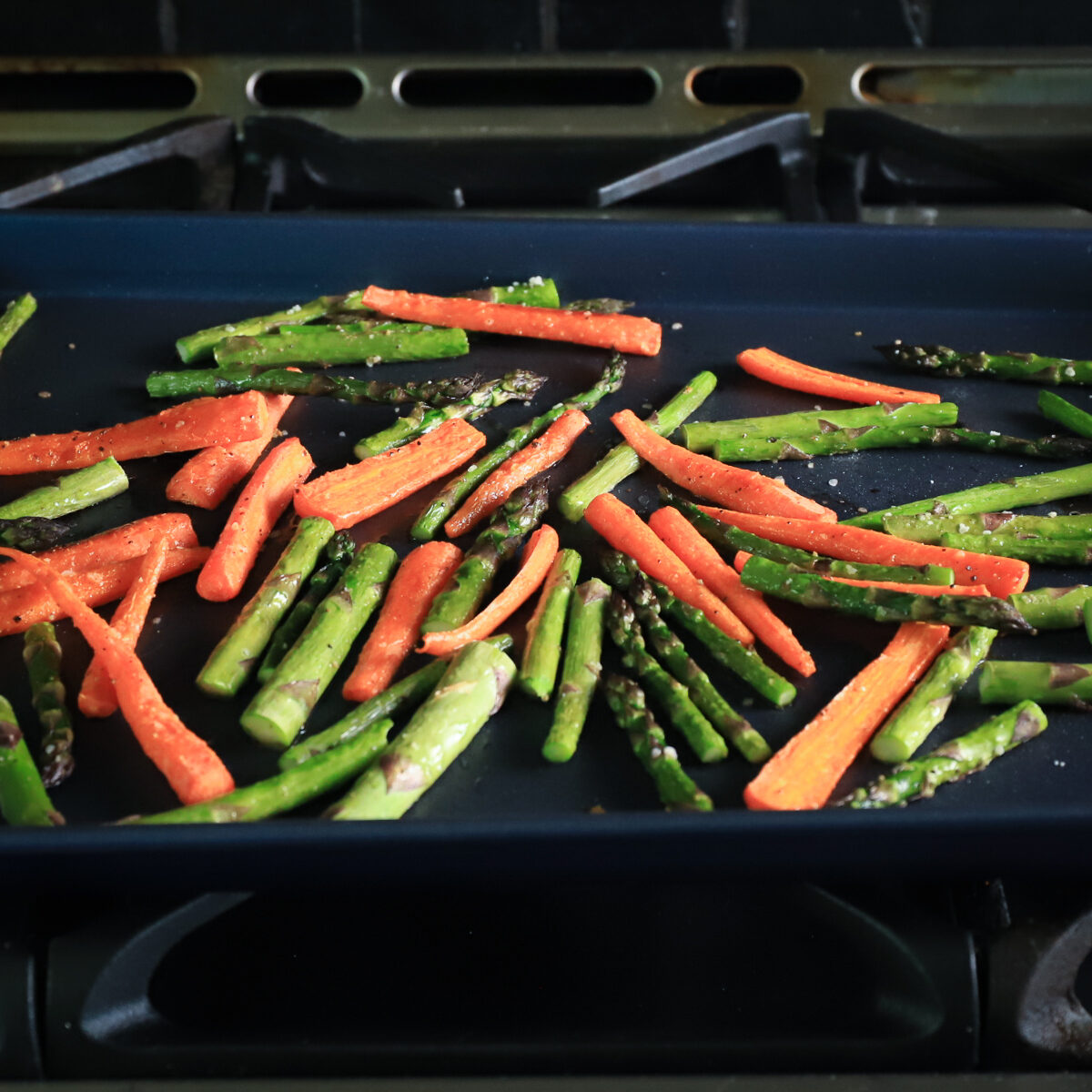 The blue pan holds the roasted carrots and asparagus pieces. You can see they are deeper in color and have a few brown spots.