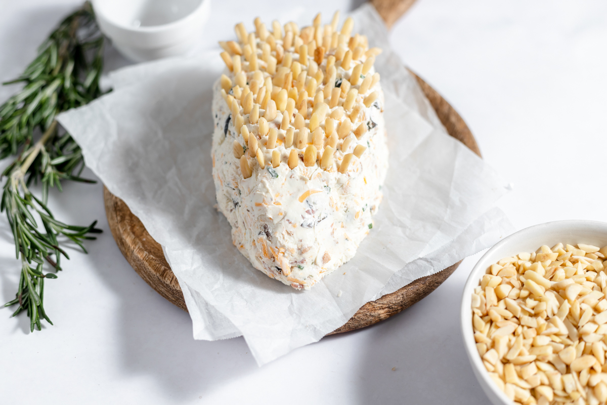 The formed cheeseball has slivered almonds sticking out of the top.