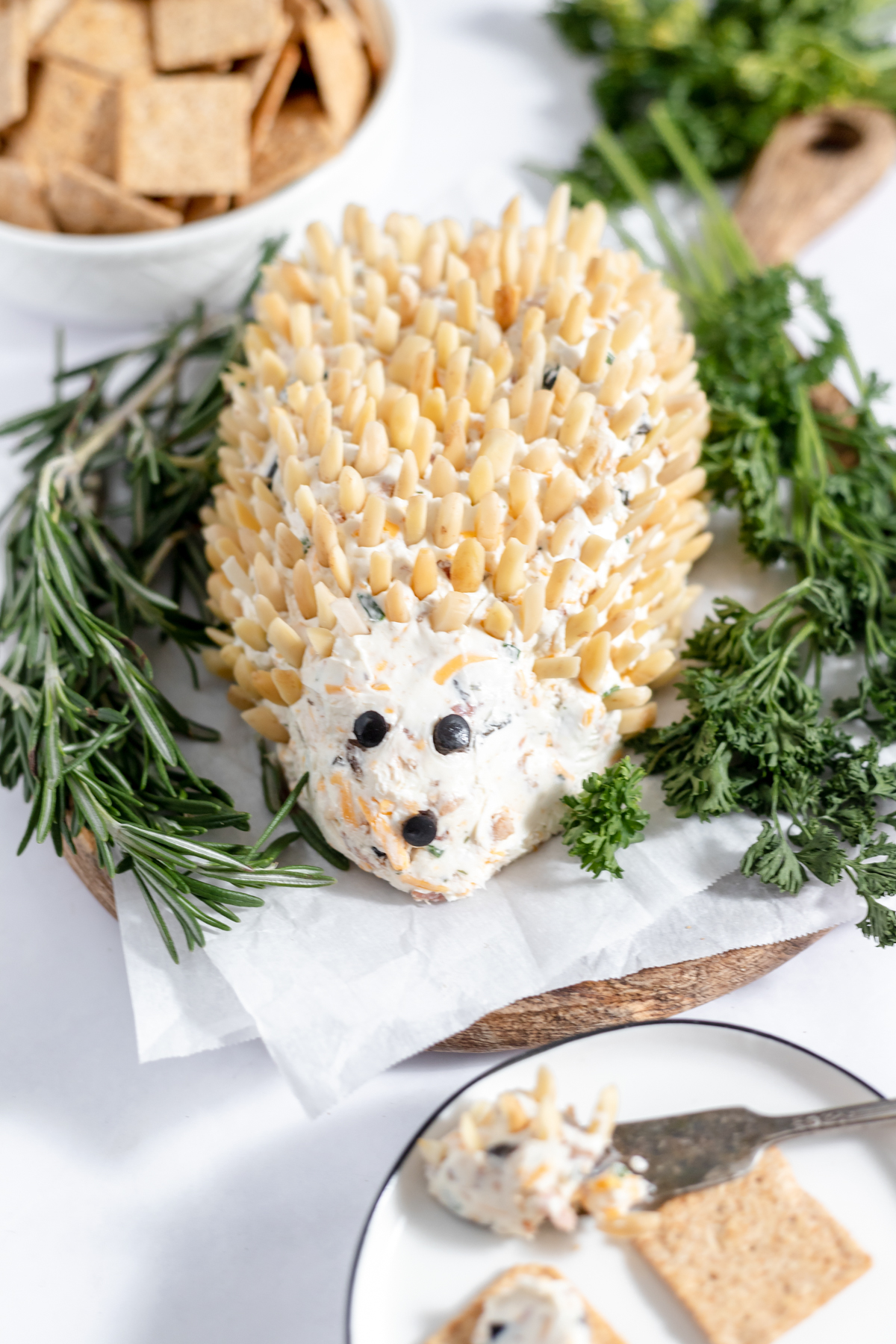 An oblong cheeseball in the shape of a hedgehog with slivered almond spikes all over.
