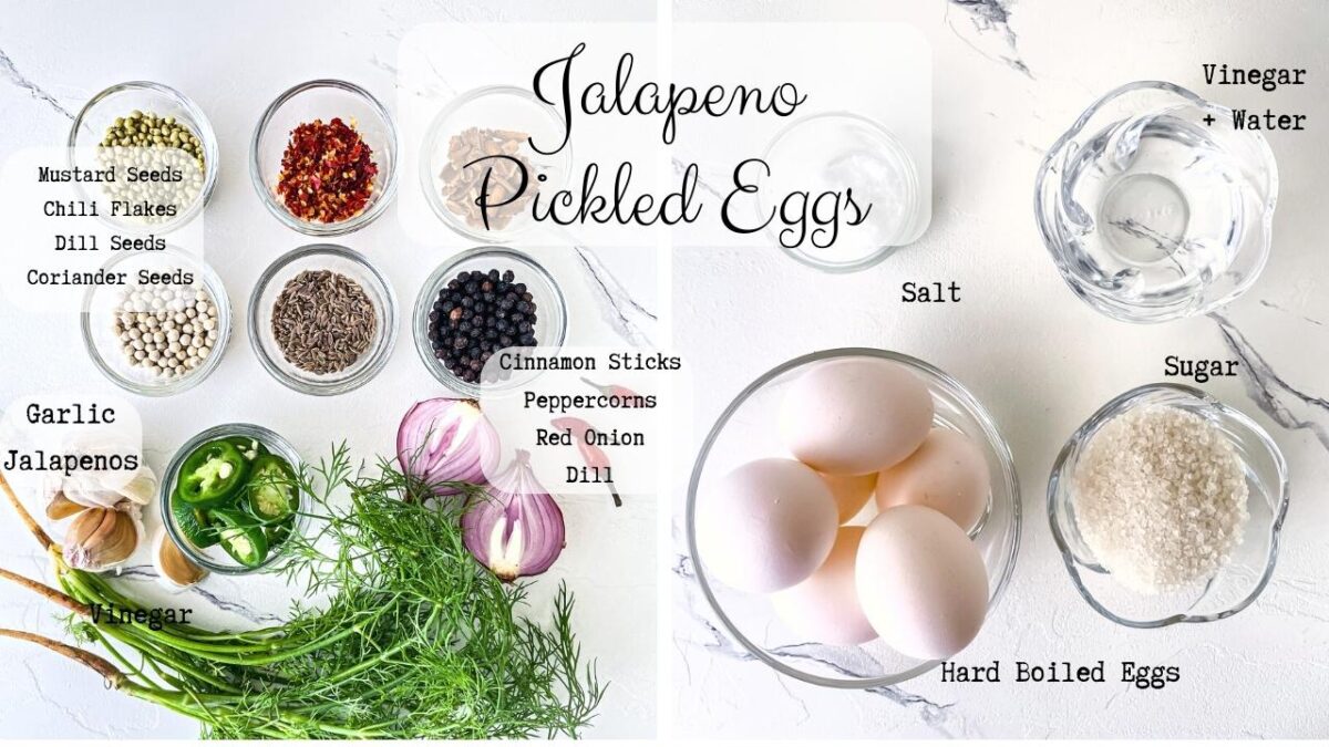 Text labelled ingredients photo for jalapeno pickled eggs. Shown are 6 spices in clear glass dishes, dill fronds, garlic cloves, chili peppers, sliced jalapeno, sliced red onion, pale pink and peach eggs, clear vinegar and water mixture, salt and sugar.