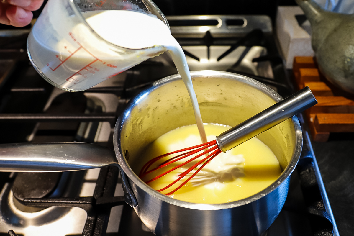 Cream being poured into the roux and stock mixture.