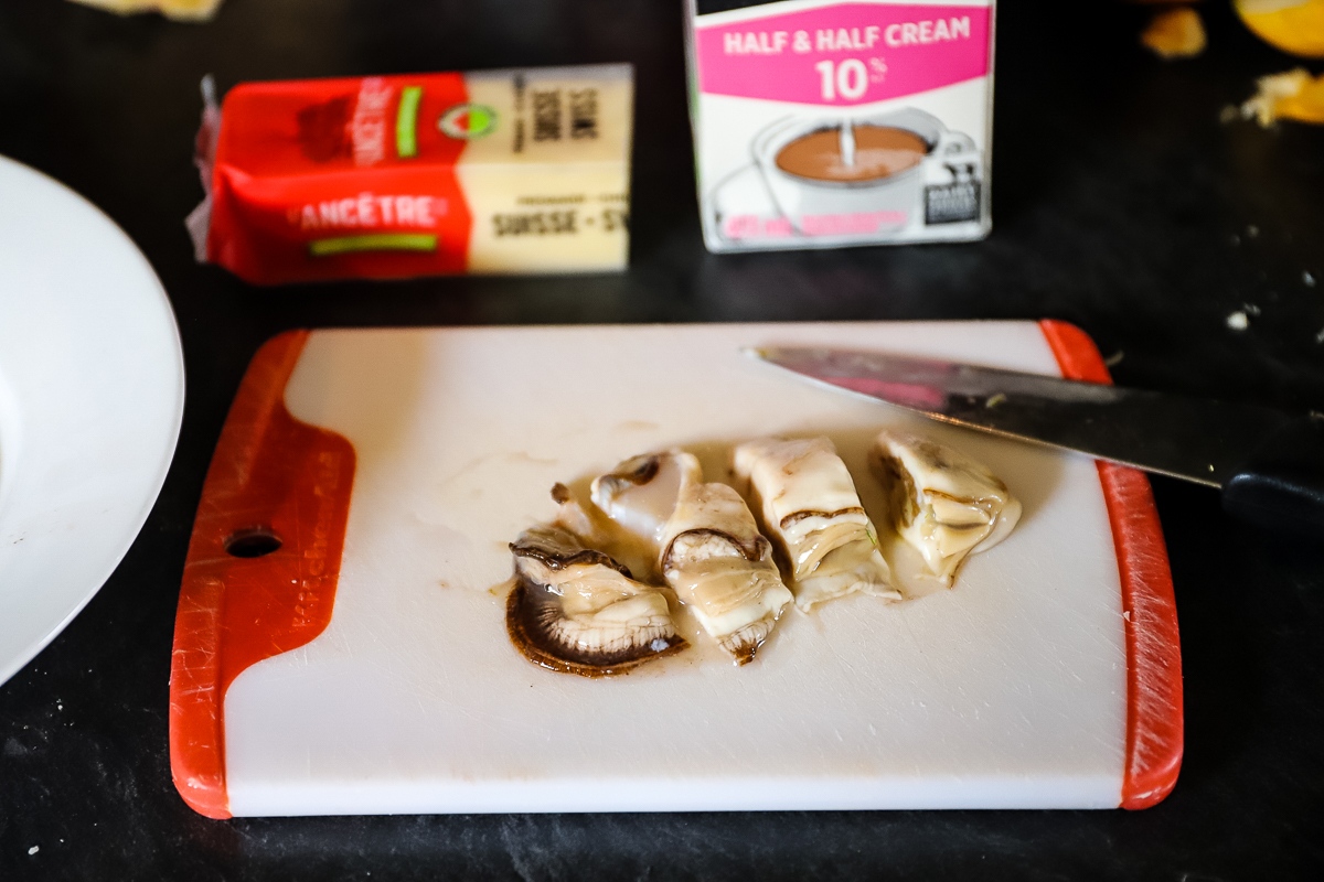 A large oyster on a cutting board has been sliced into 4 equal pieces.