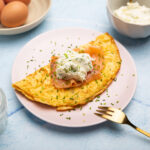A simple looking folded omelet topped with salmon and cream cheese and dusted with chopped herbs.