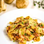 Pappardelle with a light Bolognese sauce made with walnuts and mushrooms all in a white bowl.