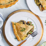 Lentil and mushroom pot pie cut in wedges on a plate with lovely pie pastry top.