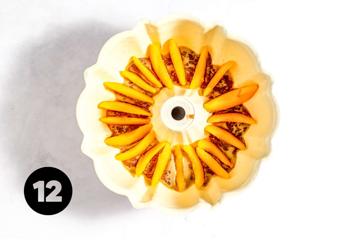 Sliced peaches are arranged in a circle around the bottom of the bundt pan, on top of the melted butter and brown sugar mixture.
