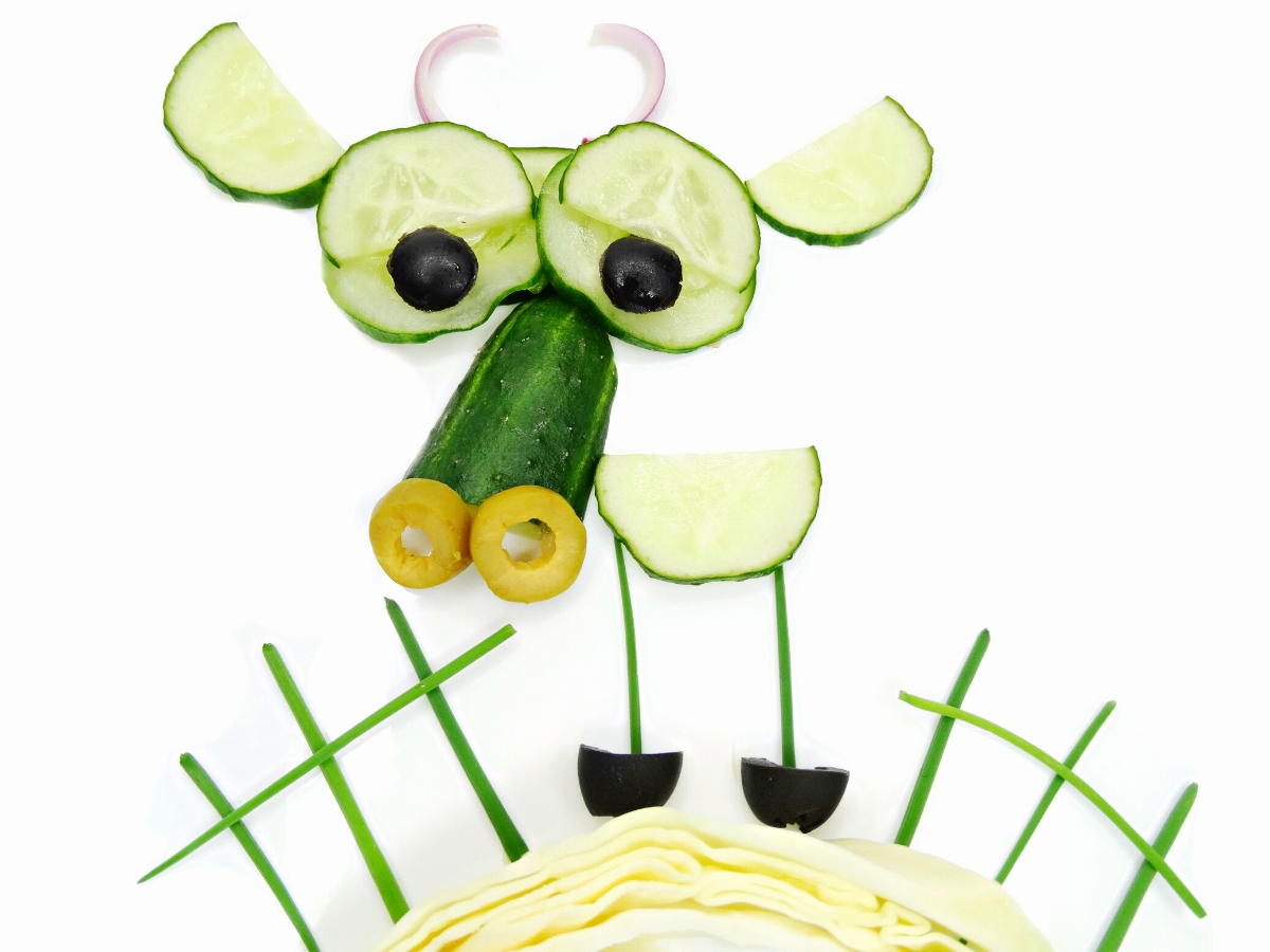 Cow made out of cucumber slices, olives and red onion slice.