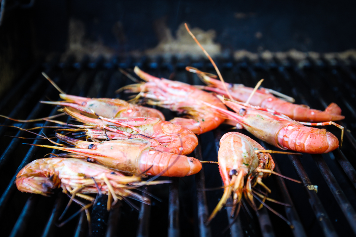 Cooked large Pacific shrimp on the grates of a grill.