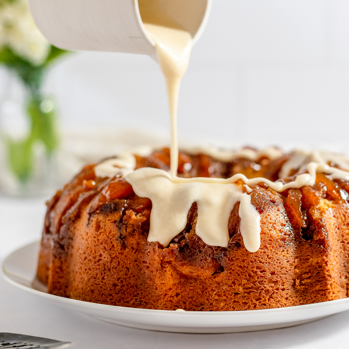 A bundt cake with creamy icing being drizzled over the top.