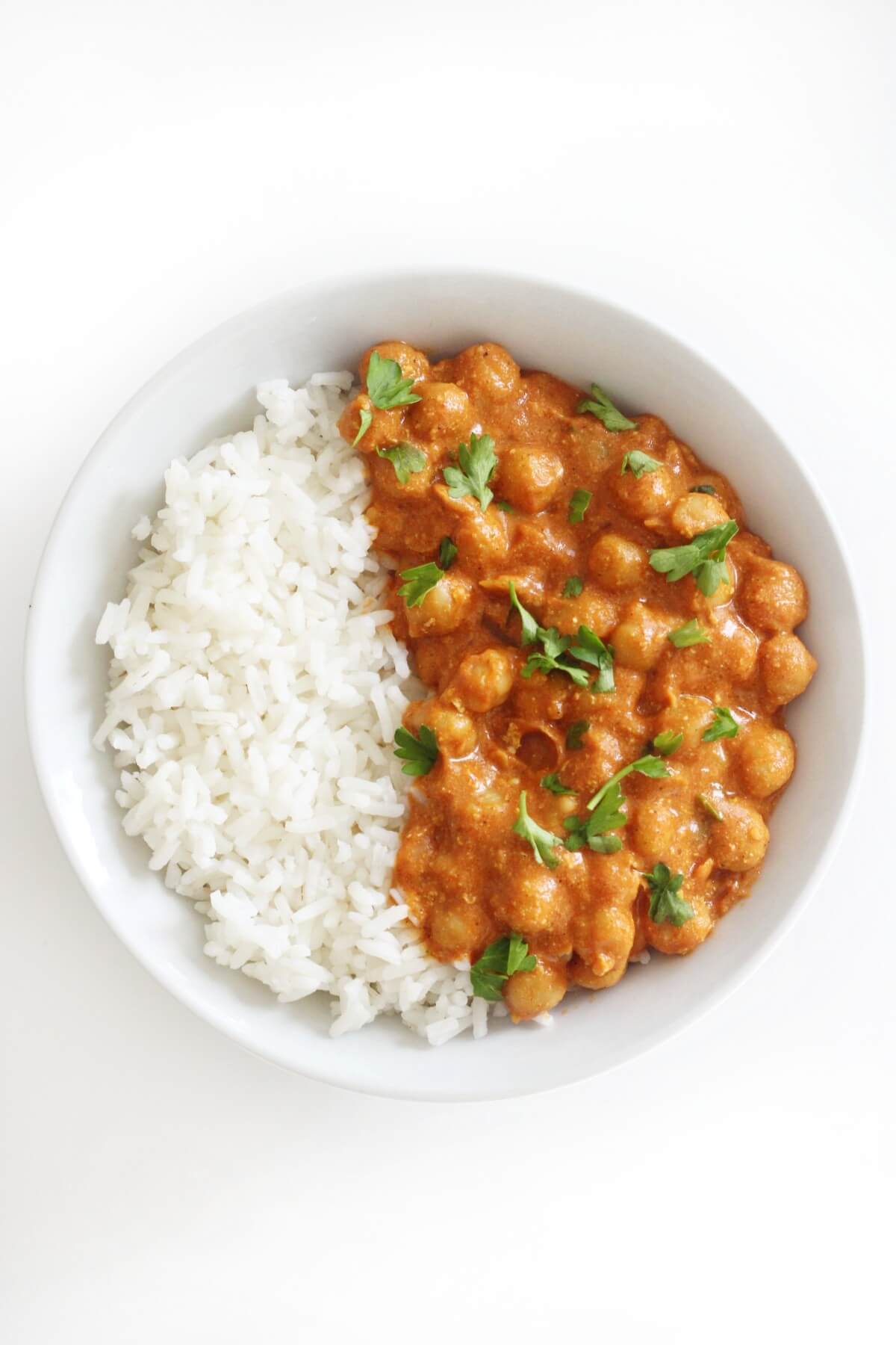 A bowl with the left half white rice and the right half chickpea curry.