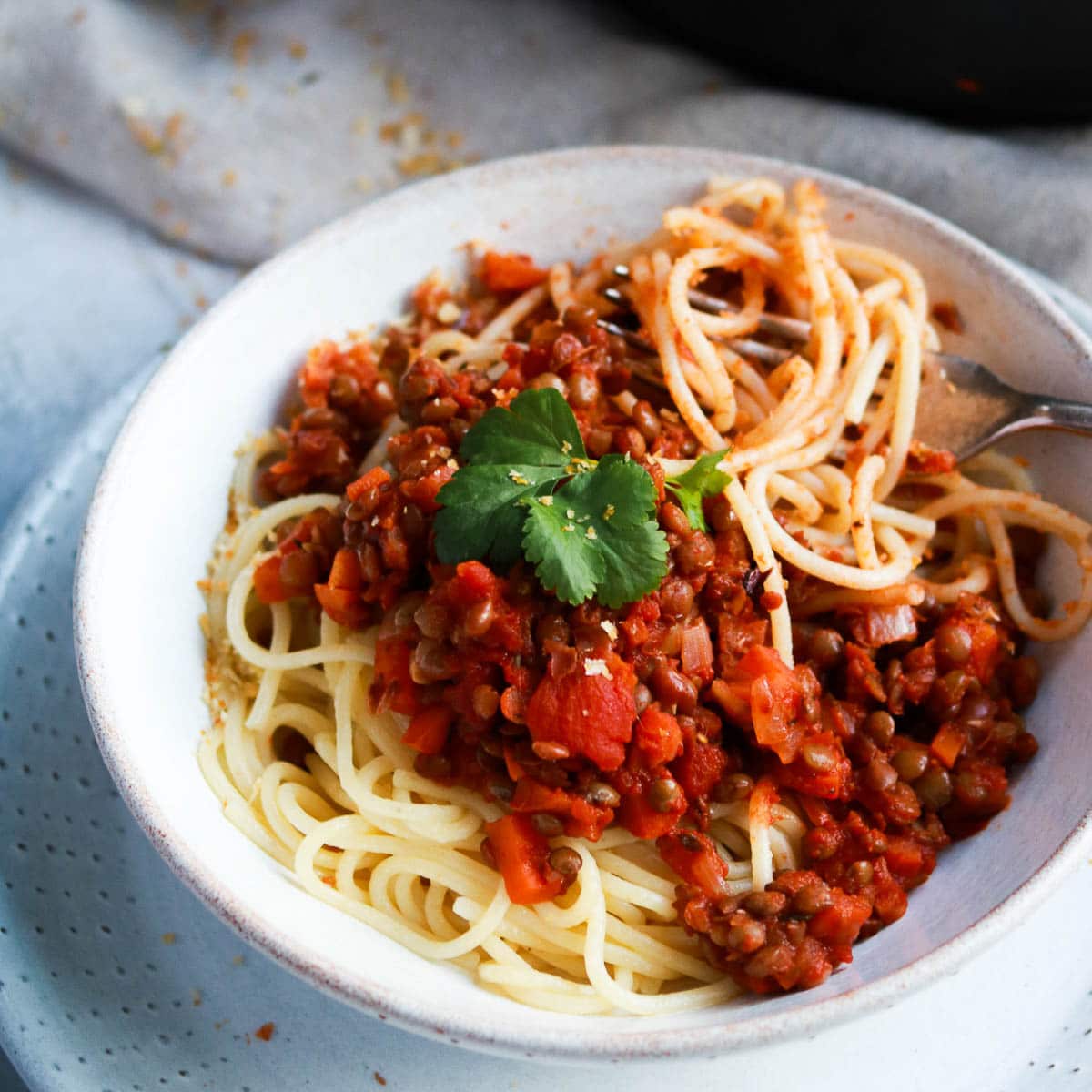 White bowl of spaghetti and lentil Bolognese sauce.