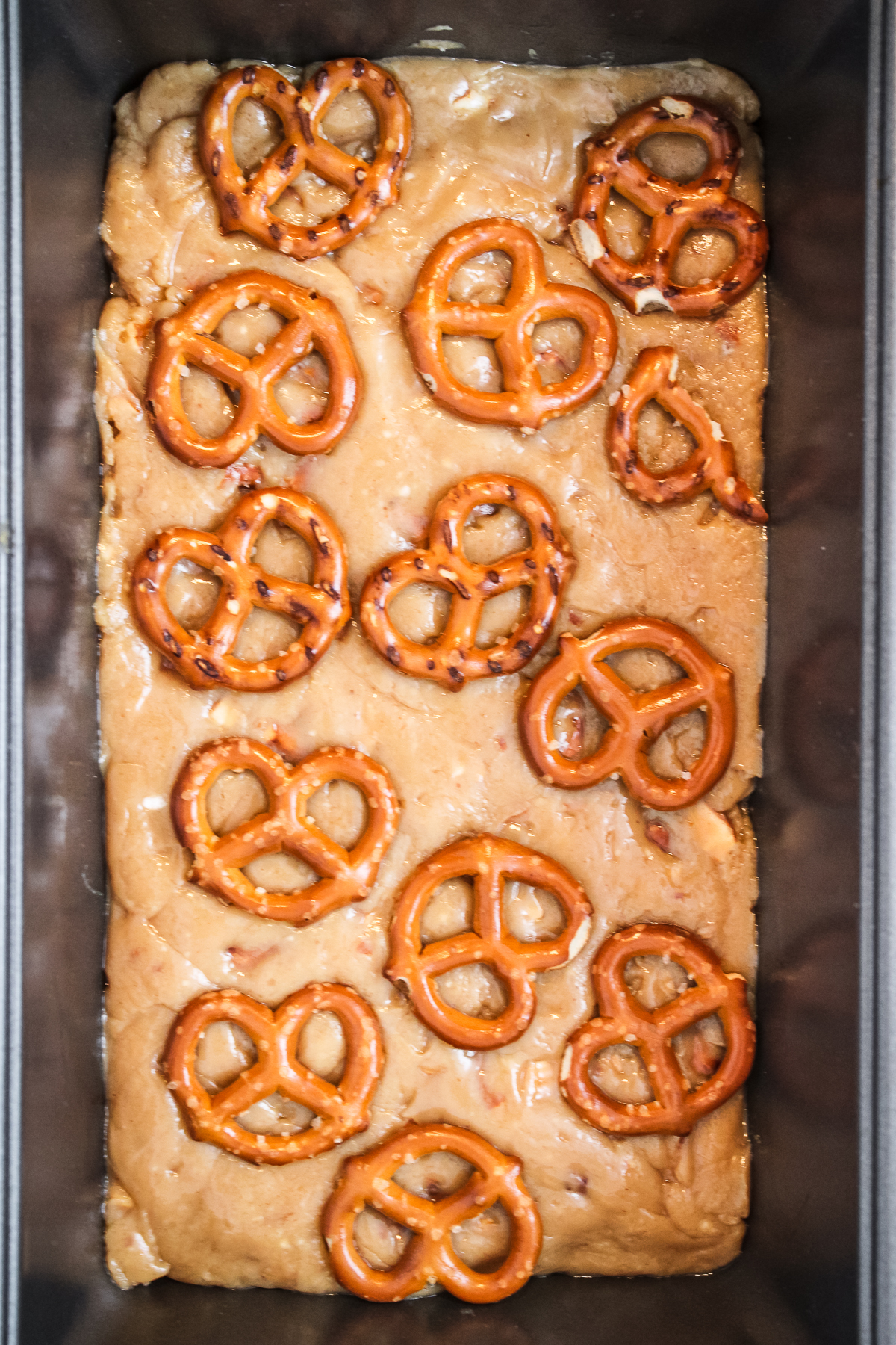 Mini pretzel twists are scattered all over the top of the peanut butter fudge and gently pressed in to stick.