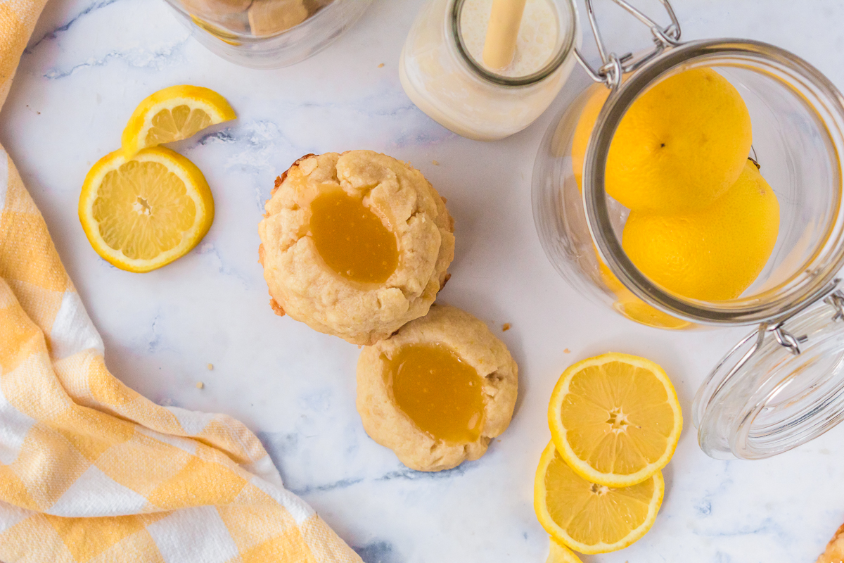 Cookies on the counter with lemon and a glass of milk surrounding them.