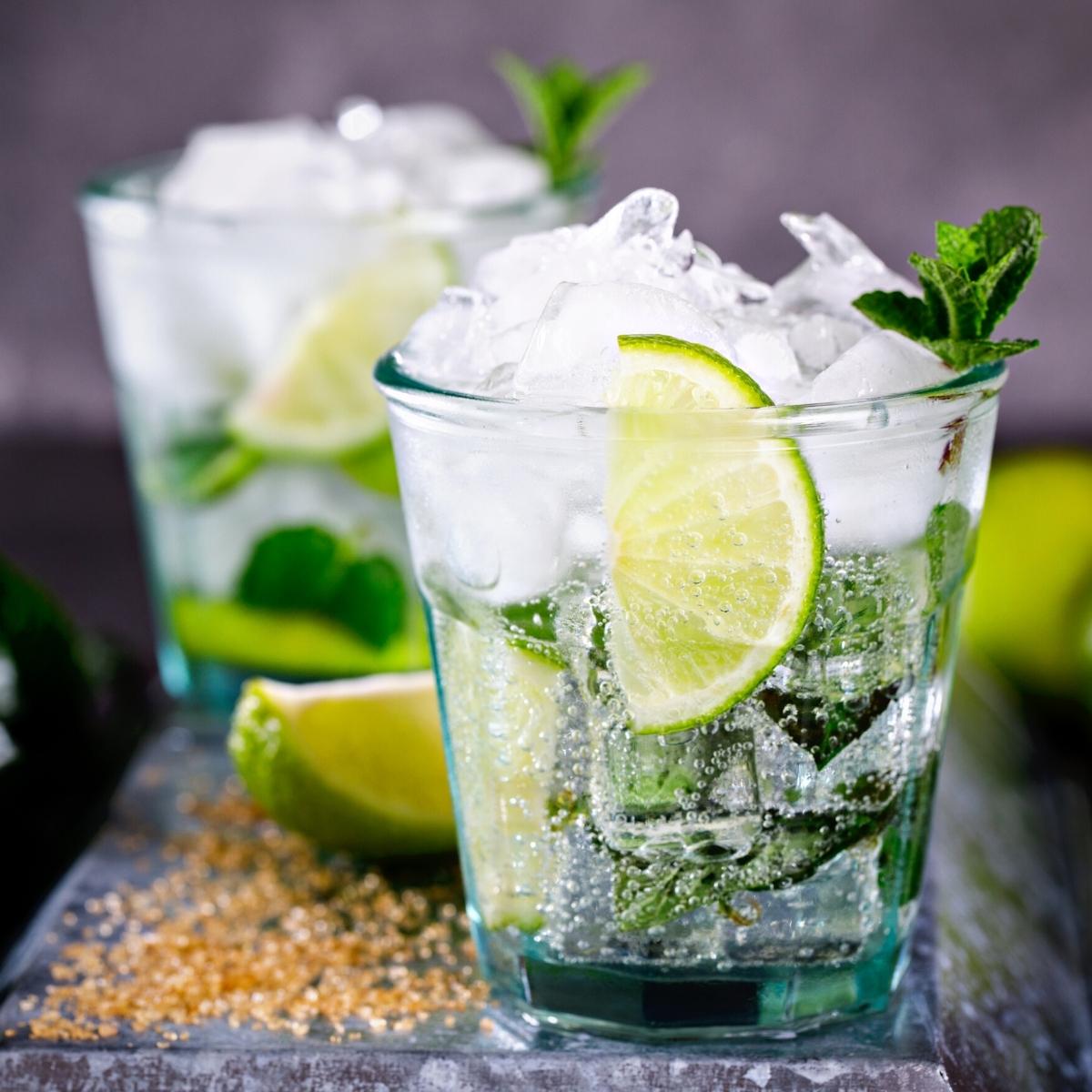 Rocks glasses filled with ice, fizzy water, lime wedges and mint.
