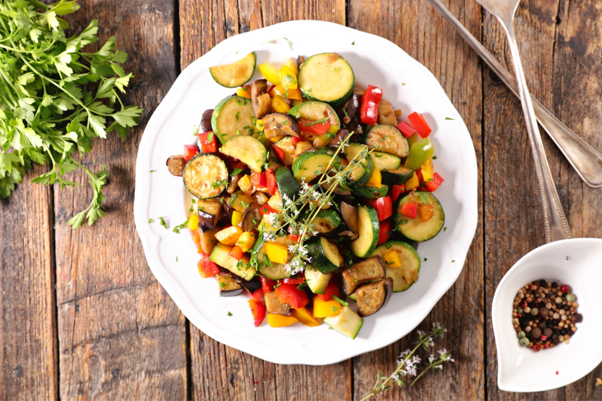 A bowl of colorful vegetable stew on a wooden table.