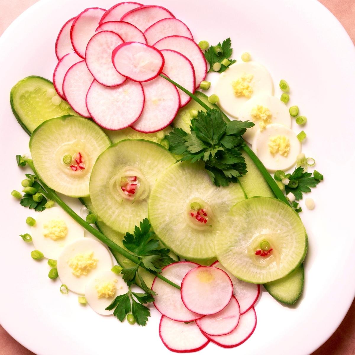 Raw sliced radishes and turnips as a salad on a white plate.