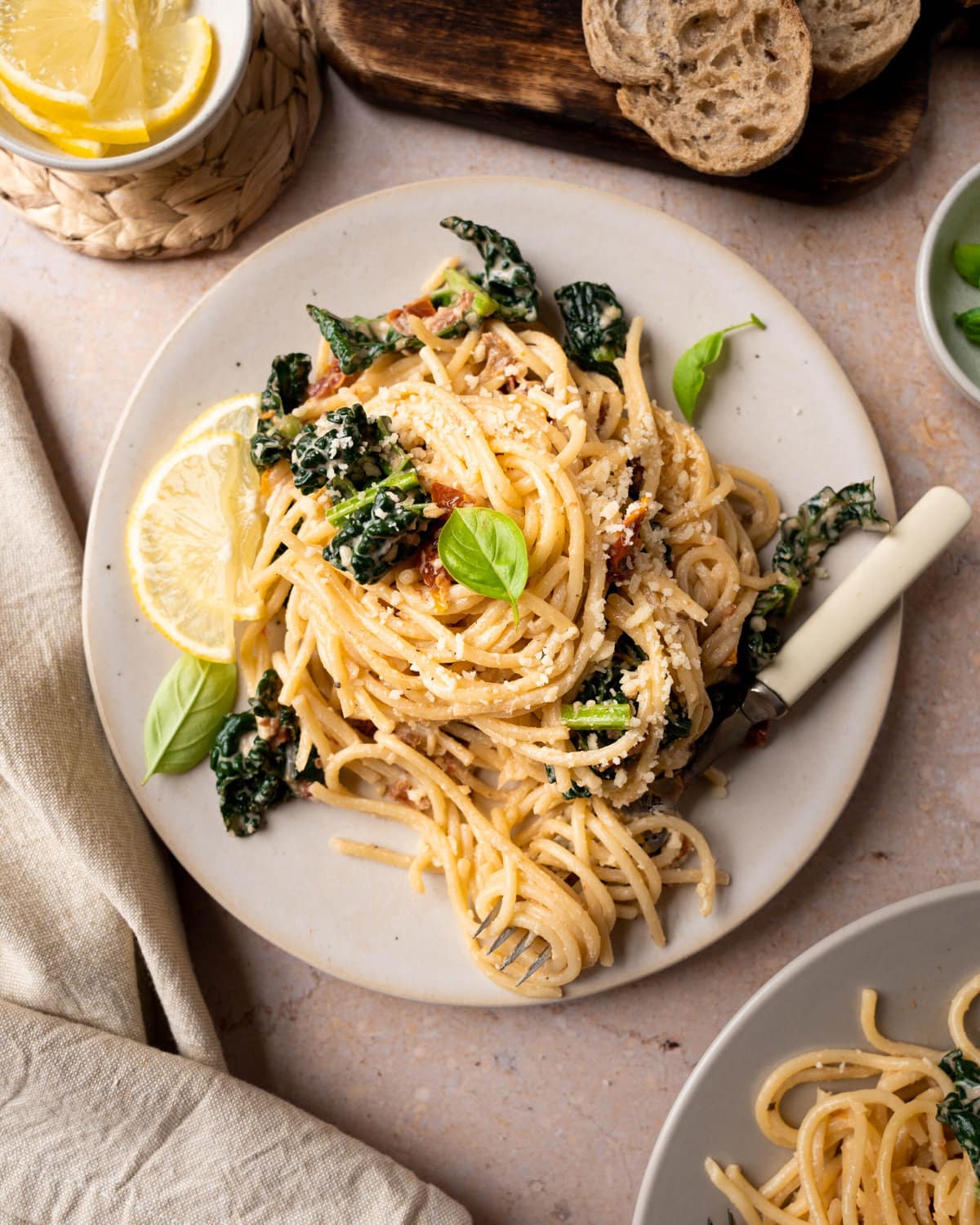 Simple spaghetti noodles and kale garnished with basil on a white plate.