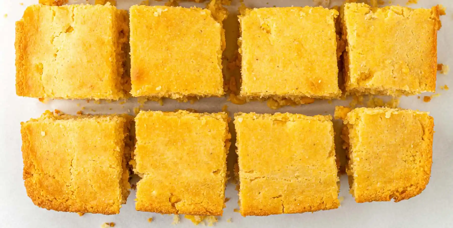 8 perfect squares of bright yellow cornbread in two rows.