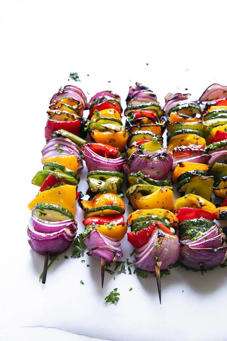 Colorful vegetable skewers including red onion, yellow peppers, red peppers and green slices of zucchini.