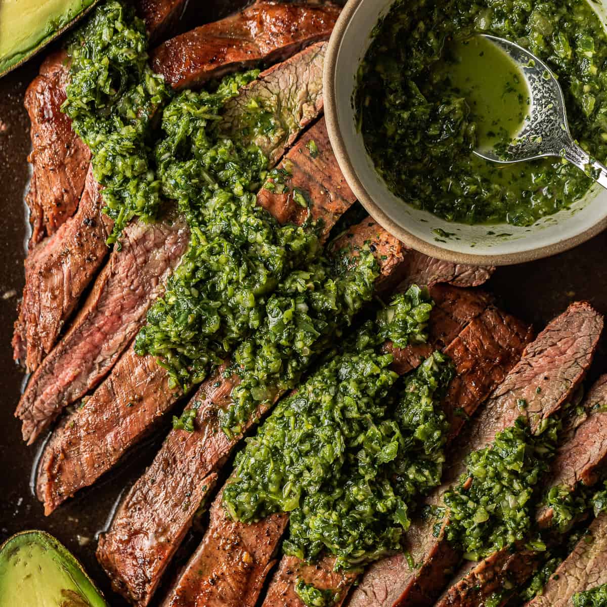 Traegar smoked steak that's sliced and dressed with green chimichurri sauce.