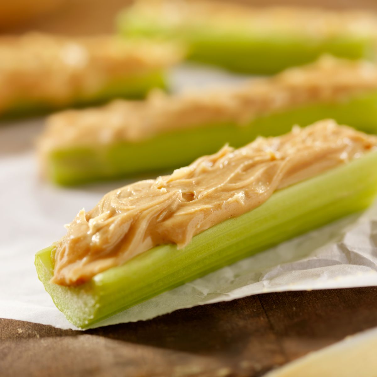 Pale brown hummus on top of celery sticks.