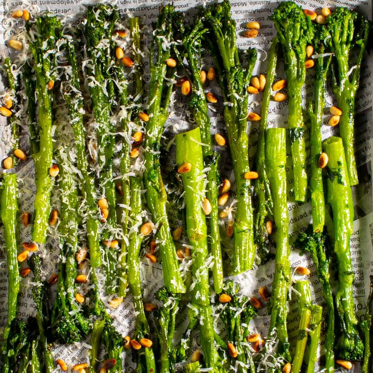 Long green cooked stalks of broccolini topped with slivered nuts.
