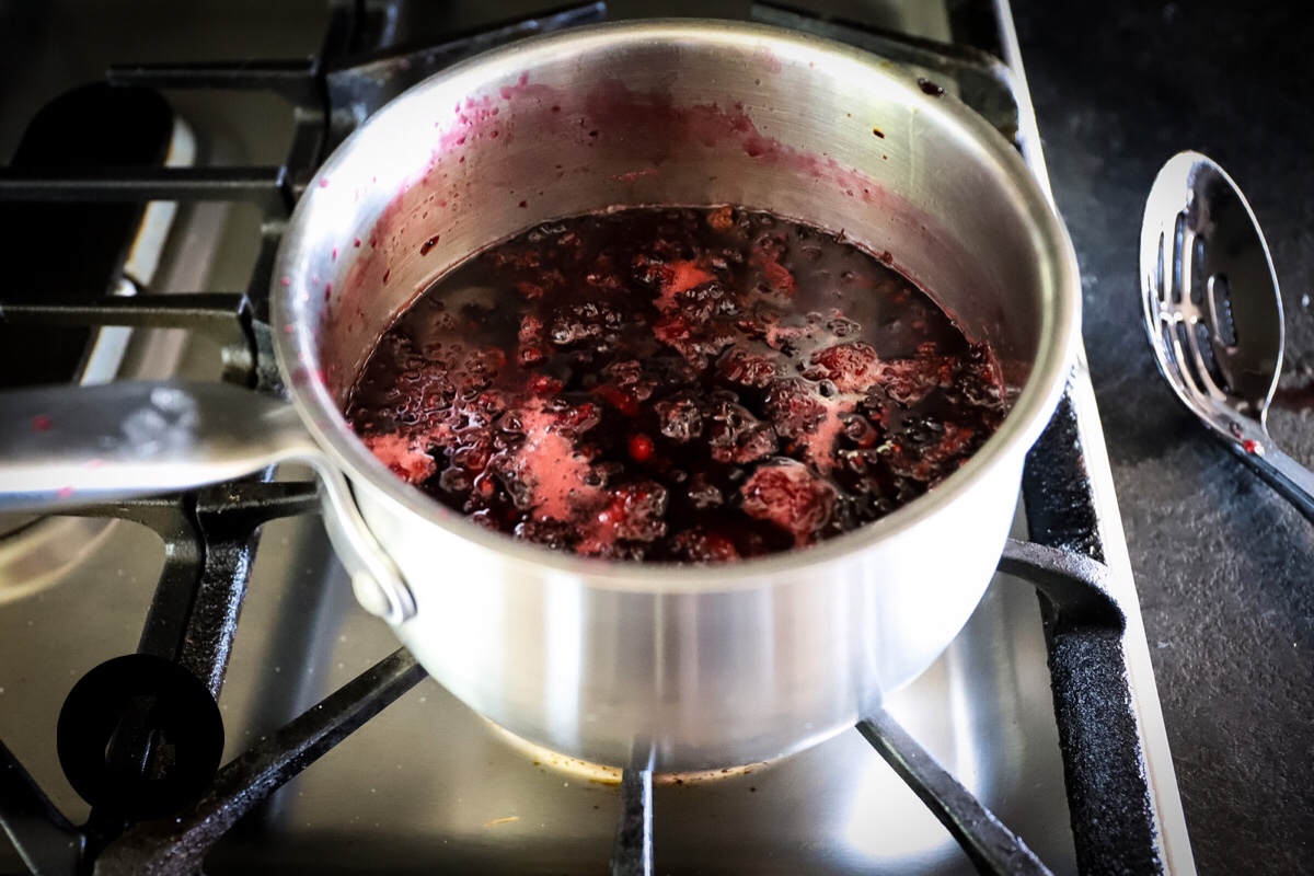 The cooked syrup is dark purple-pink and has left a pink ring inside the pot and is cooling.