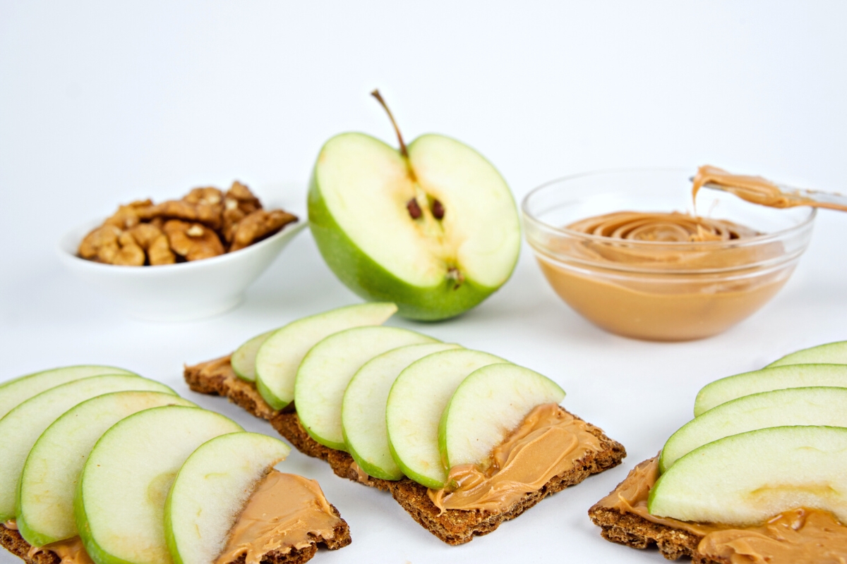 Apple slices on long rectangle crackers spread with peanut butter.